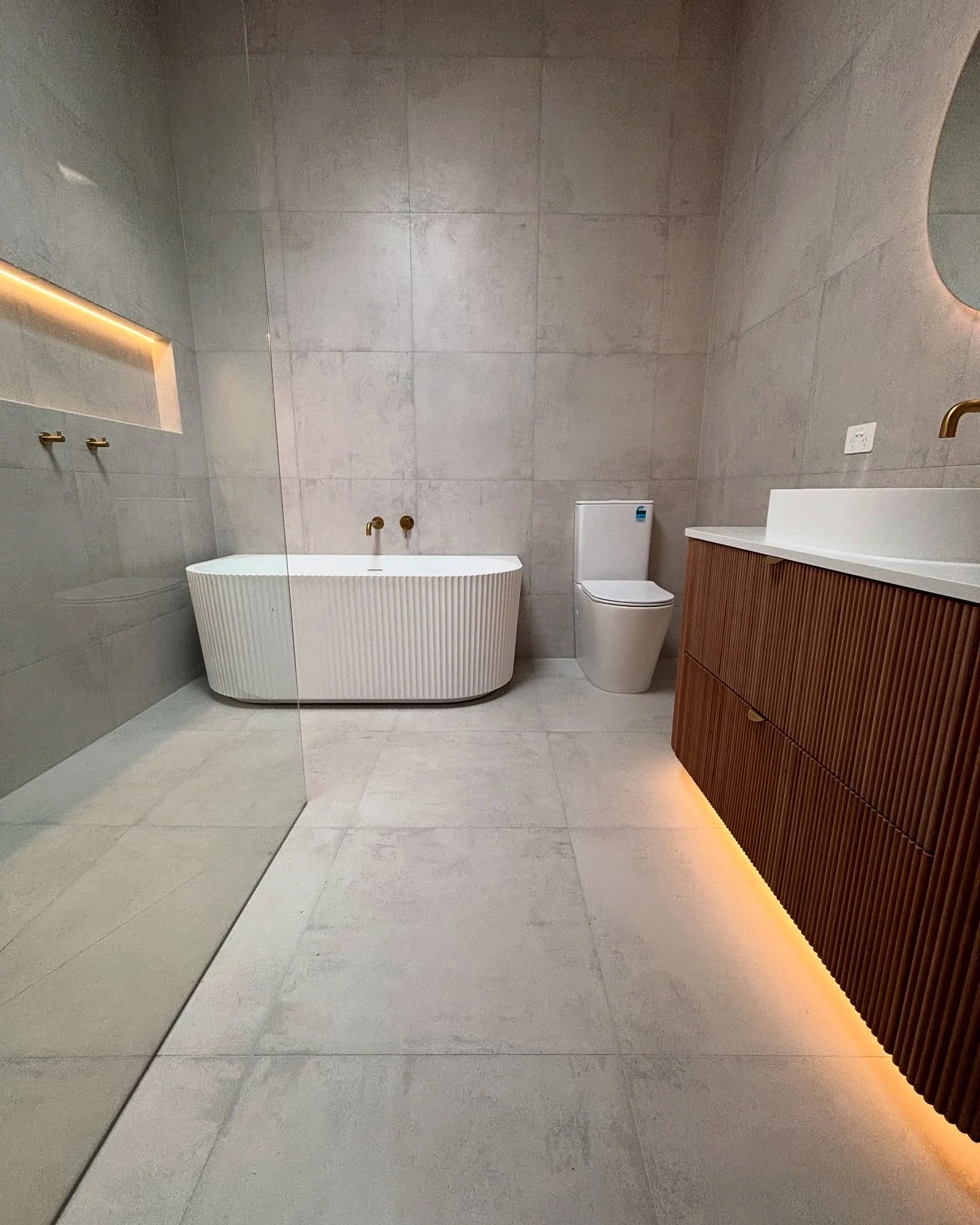 Finished Frankston South bathroom with a freestanding bath, fluted timber vanity and warm lighting